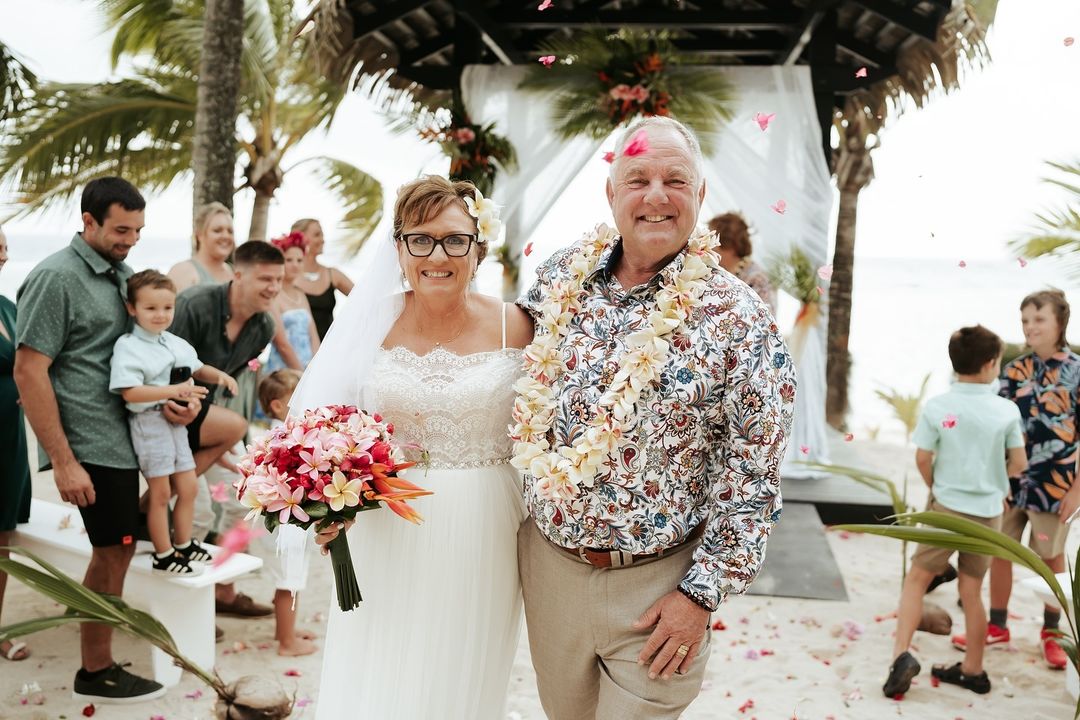 A joyful couple celebrating their dream beachfront wedding at Edgewater Resort, Rarotonga, surrounded by family and tropical beauty.